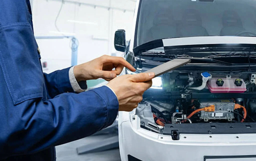 serviceman-with-digital-tablet-next-to-electric-van-with-open-hood